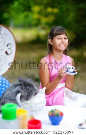 Girl sits at table and holding a cup of tea. Alice in Wonderland concept