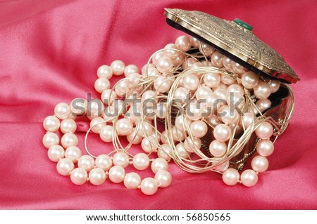 Pearl necklace and silver jewelry in metal box, on pink silk