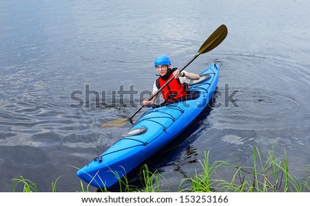 Young man riding around lake on kayak. Sports and recreation