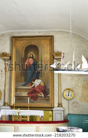 ALAND,FINLAND - AUG 17,2014:Eckero church is consecrated to Roman martyr St Lawrence.Present altar painting,Christ and Sinful Woman,ordered from artist Reinhold in 1876,hides walled-in chancel window