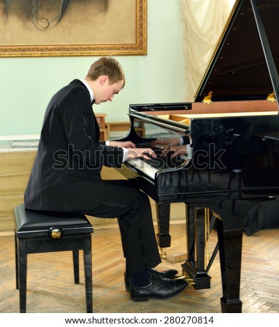 Elegant young pianist plays on black grand piano