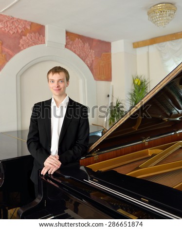 Smiling pianist next to black grand piano
