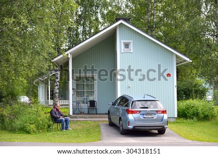 OULU, FINLAND - JULY 13, 2015:Nallikari Holiday Village-Camping is holiday resort near centre of Oulu on island Hietasaari. Near small cottage it is good to sit with book in shadow of trees