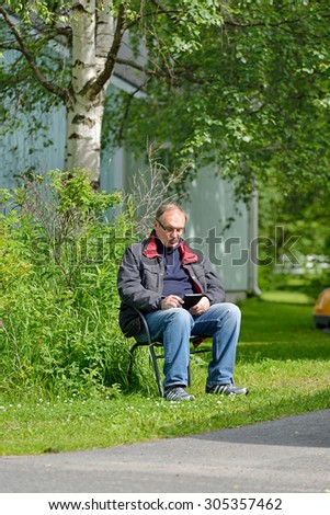 Middle-aged man sitting under tree and read e-books