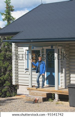 Young man on the porch of a cottage in the woods
