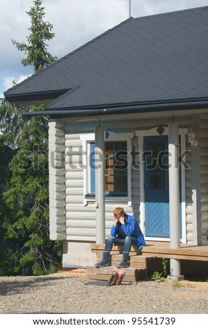 Young man on the porch of a cottage in the woods
