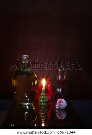 Still life with rose, fired candle and wine