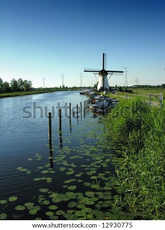 the traditional Kinderdijk wind mills of Holland in a calm water canal, bordered with water lilies