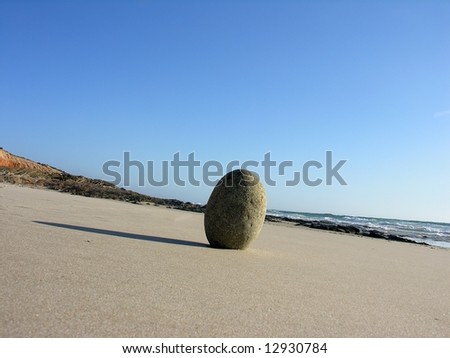 A lonely egged shape rock in a desert beach, in the south west coast of portugal