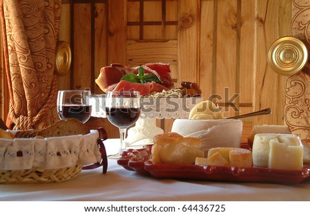 Table settings for a special occasion. Cheese assortment, bread and red wine in a glamorously styled room