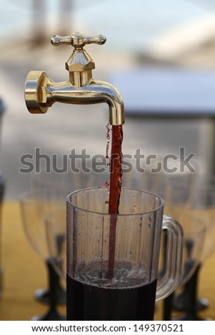 red wine on a glass carafe flowing from a magic faucet