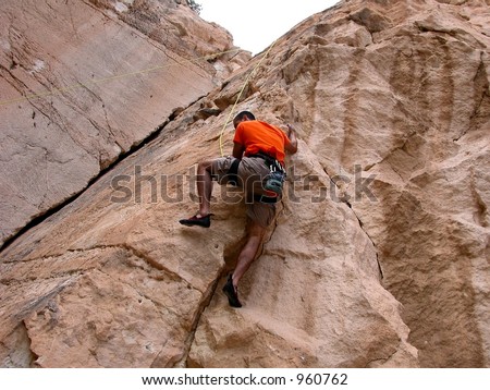 Climber works his way up the overhang of a stone wall