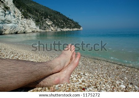 Looking at feet in water sand and stones of Southern Italy
