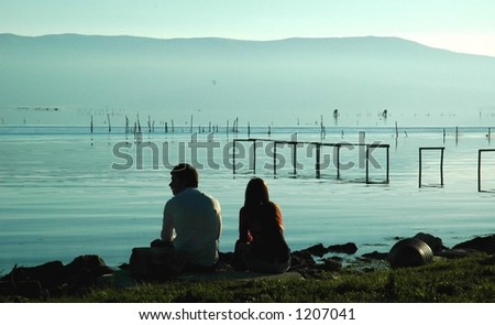 a couples sits a at lake at sundown in southern italy