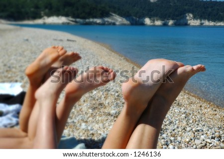the feet of three tanning girls on the beach in southern italy