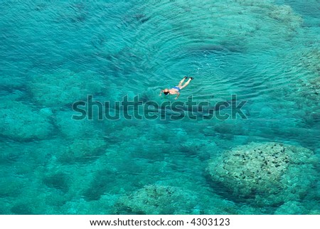 man snorkeling in clear coral waters