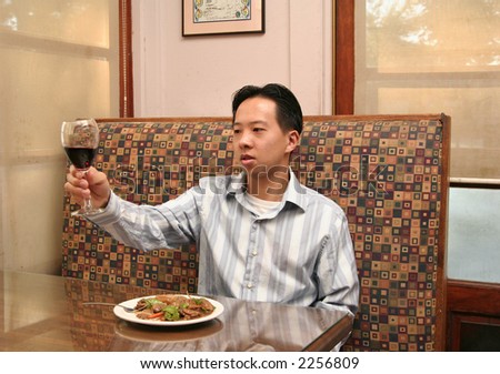 business man hold up wine glass with cheering pose with unseen partner