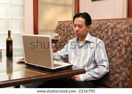 business man drinking wine during lunch while working with his laptop
