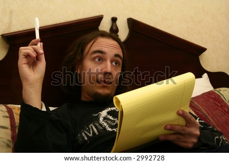 long haired man holding pen and note book get an idea