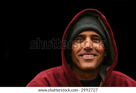 portrait of a urban man wearing jacket with hood smiling on black background