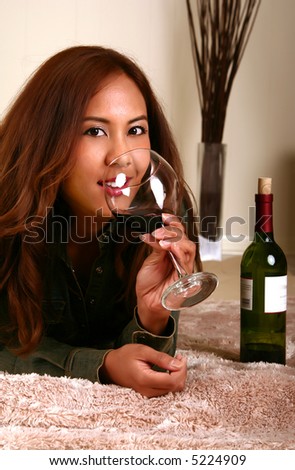 shot of woman drinking wine on her bed showing smiling expression