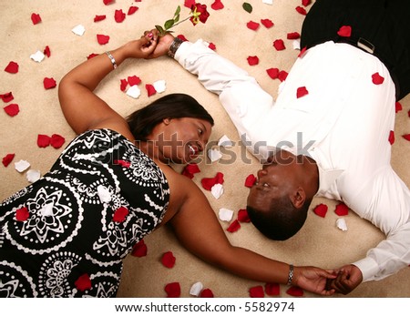 happy african american couple holding hand and laying on the floor. the woman holding a rose on her right hand