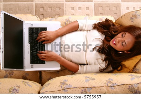beautiful model relaxing on sofa and working with computer.