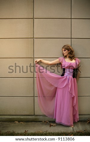 outdoor shot of beautiful caucasian girl against contemporary background with pink dress