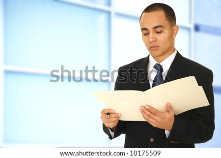 a man reading a folder while walking by his office hallway