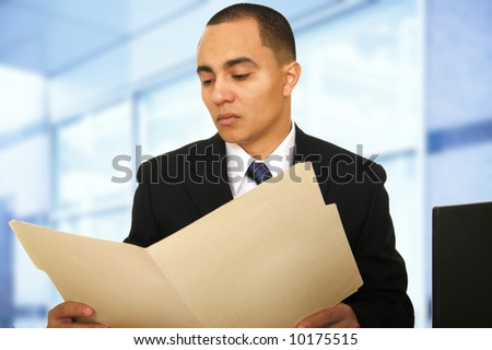 a man sit by window in his contemporary office space while seriously looking at his folder