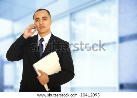 business man holding folder and making a phone call in front of his modern office setting