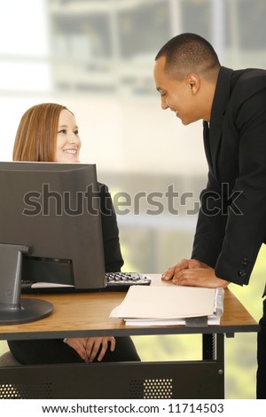 shot of two business people talking in light office environment. both showing happy expression. concept for business chat or business team
