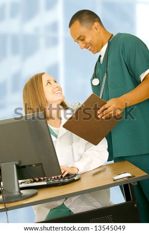medical staff working together in office environment. the woman in white coat sitting and the man in nurse uniform standing