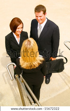 three business people having informal chat under stair. the business man is holding his suitcase