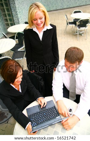 top view of one business woman standing and two other business people looking at laptop. outdoor with modern setting