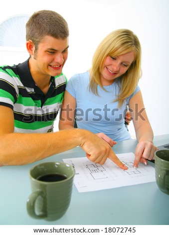 happy young caucasian couple looking and pointing at real estate floor plan before purchasing a house