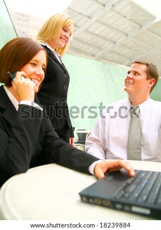 business people chating with their coworker in foreground using laptop and calling