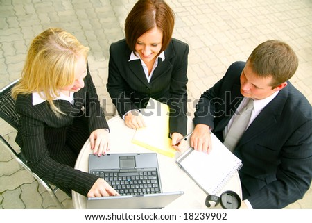 top view of blond business woman pointing at laptop, two other business people paying attention
