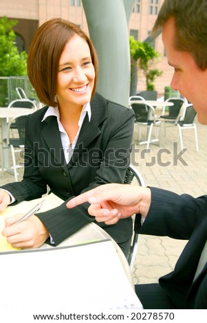 two business people discussing. focusing on the woman. outdoor in modern cafe setting