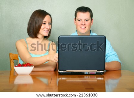 young caucasian couple discussing family business on kitchen table looking at laptop