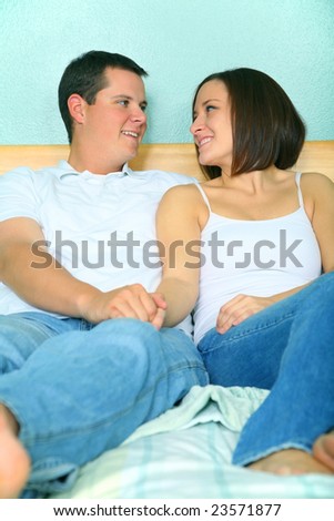 romantic young caucasian couple holding hand and sit on their bed showing happy expression