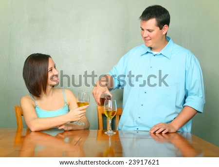 happy couple enjoying wine. caucasian male pouring wine for his girlfriend or wife