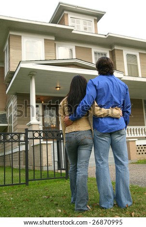 young couple looking at their house. photograph taken from back