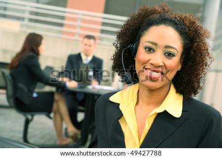 show of african american business woman wiearing headset and her colleagues on the background