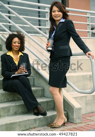 african american and asian business women are talking by stair