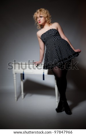 Beautiful female in polka dot dress posing next to dressing table
