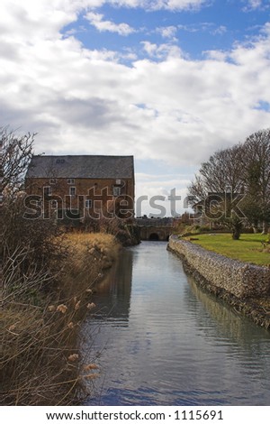 Old brick mill house and mill stream on sunny day
