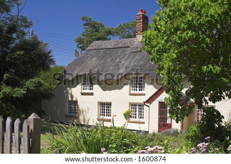 cream thatched cottage set in beautiful garden with deep blue sky.