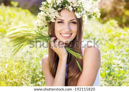 Beautiful girl on the nature in wreath of white flowers