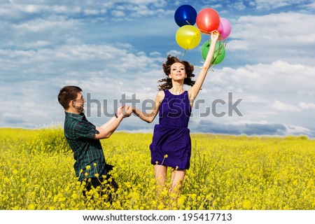 Happy couple with balloons on the yellow field
